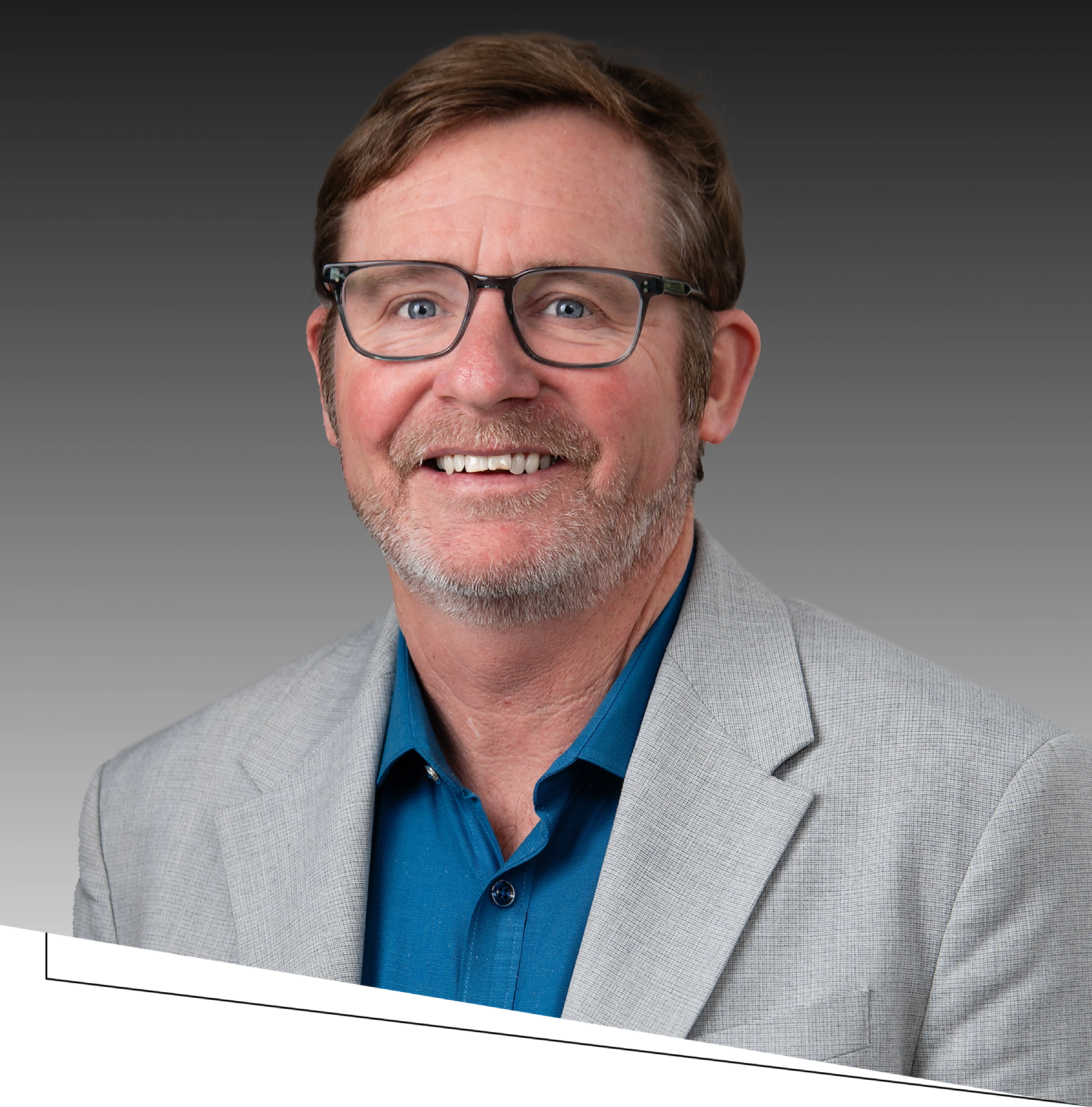 Smiling man in glasses and gray blazer.